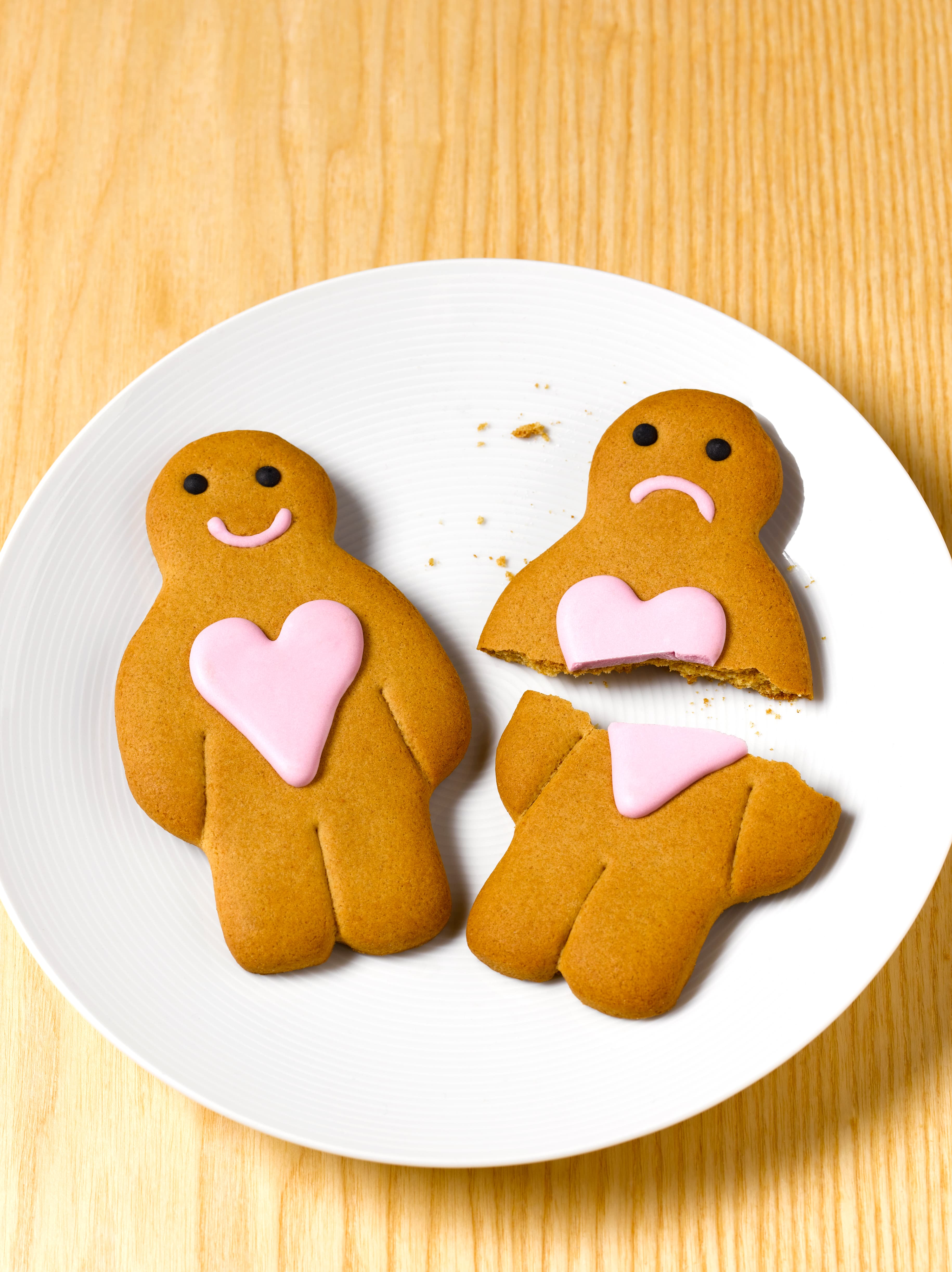Gingerbread couple laying on plate, one broken to symbolize a breakup.